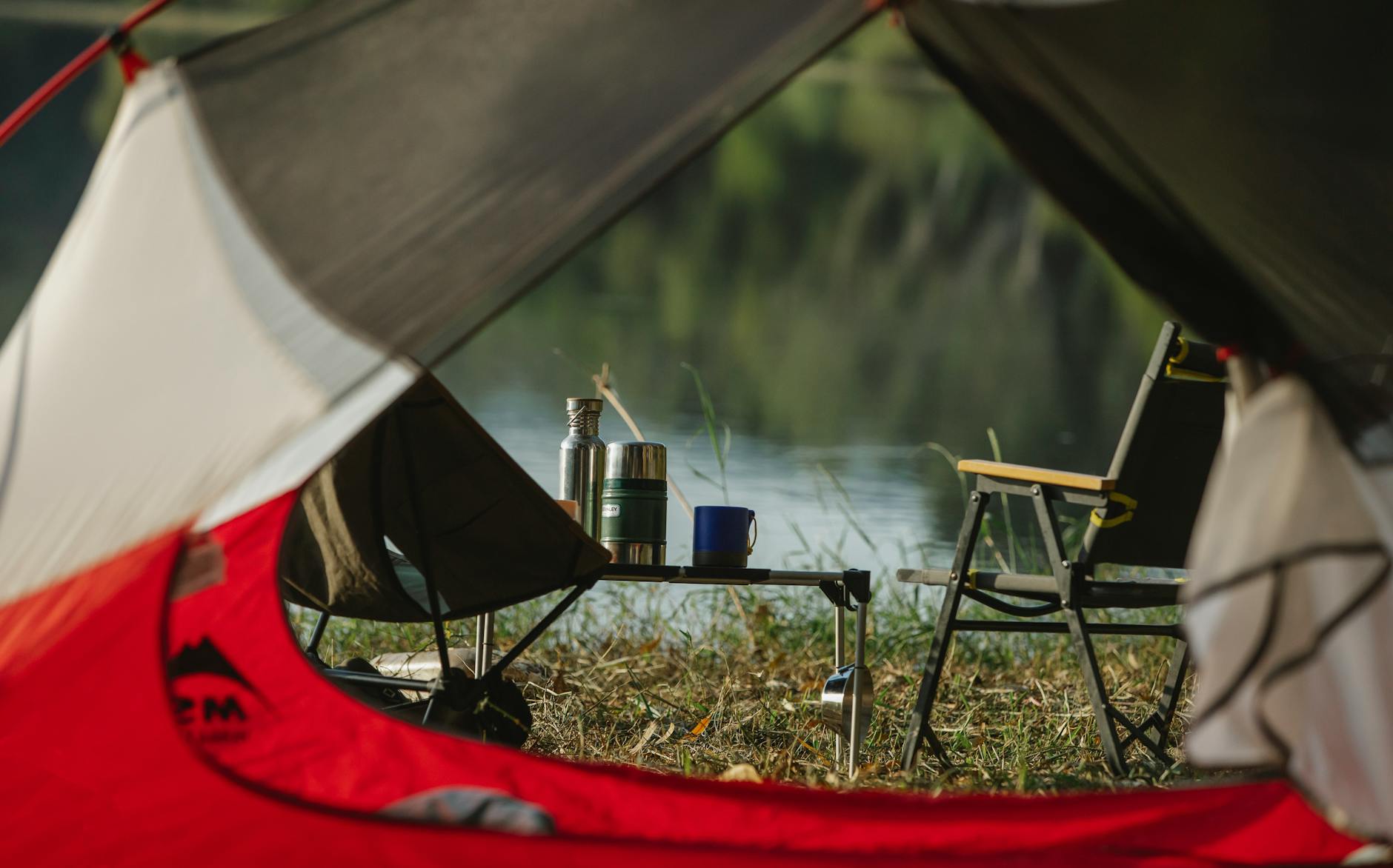 tent with camping chairs on river coast