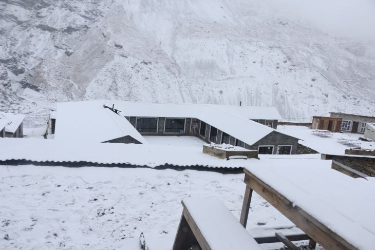 En route to Pisang Peak Climbing in the Annapurna region of Nepal, a captivating view unfolds: traditional houses with roofs blanketed in glistening snow. 