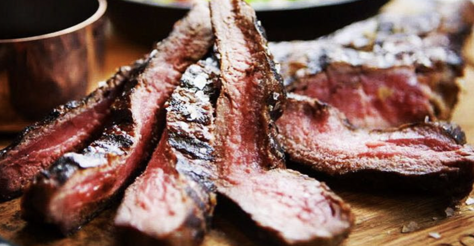 closeup of steak cut into pieces on a wooden cutting board