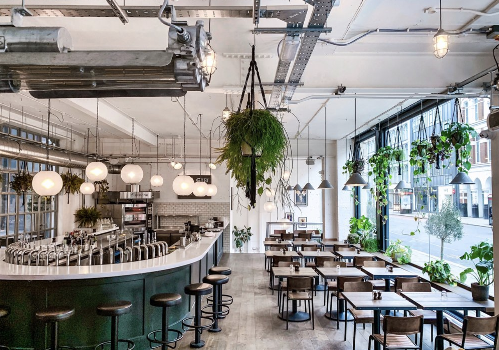 In side of Fare restaurant. There is a bar and a table area. It is empty, with indoor lighting on during daylight. you can see the street from the large window that covers one wall