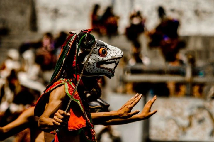Vibrant dancers in traditional Bhutanese attire performing during the Tsechu Festival.