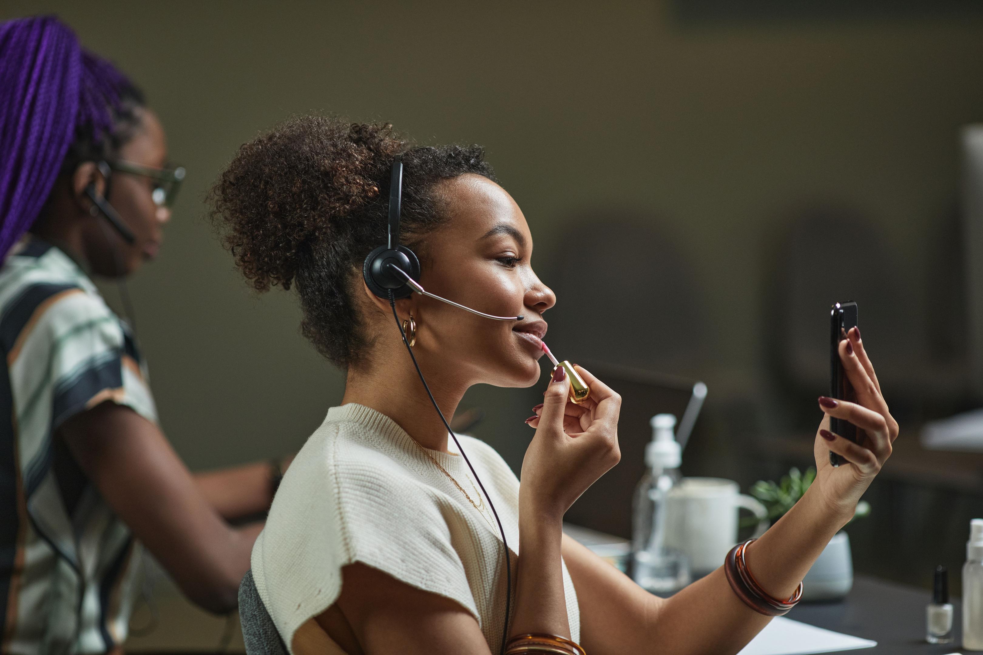 Woman touching up her makeup at her desk.