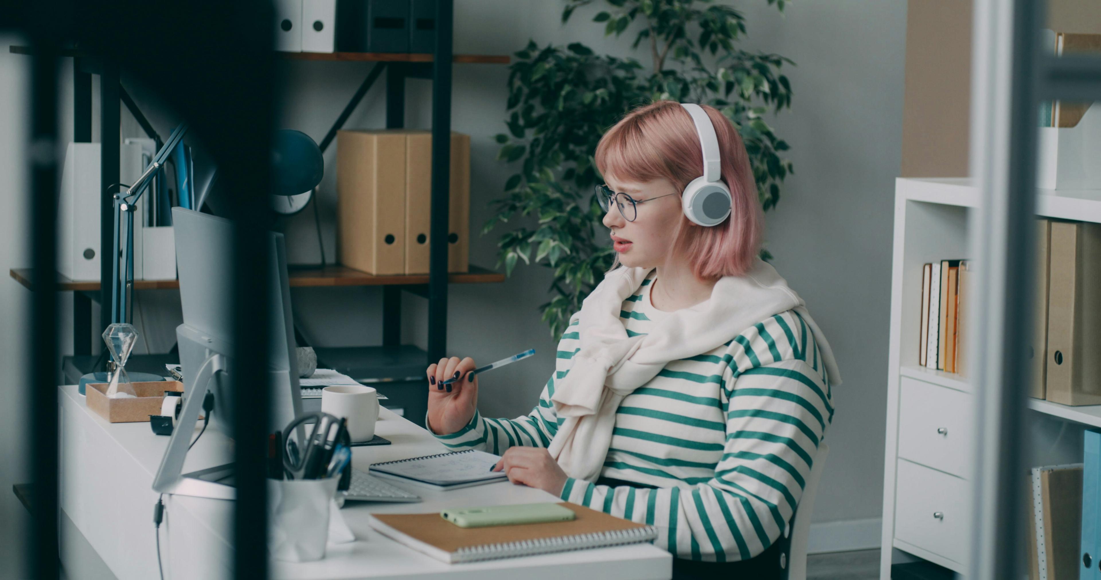 Woman working while wearing a cardigan and listening to music.