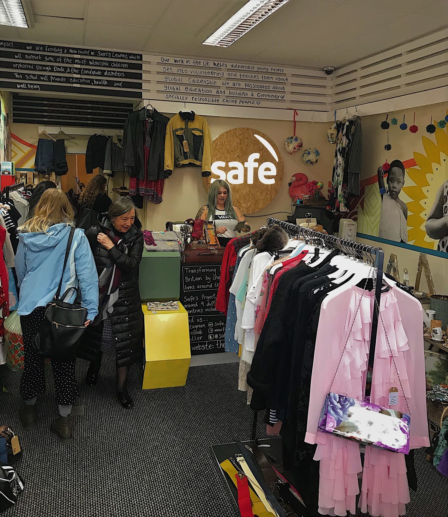 The interior of the Safe Ethical Boutique with customers browsing and various clothes on display.