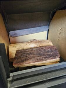 Top down fire lighting method with kiln dried hardwood logs at the base of the stove