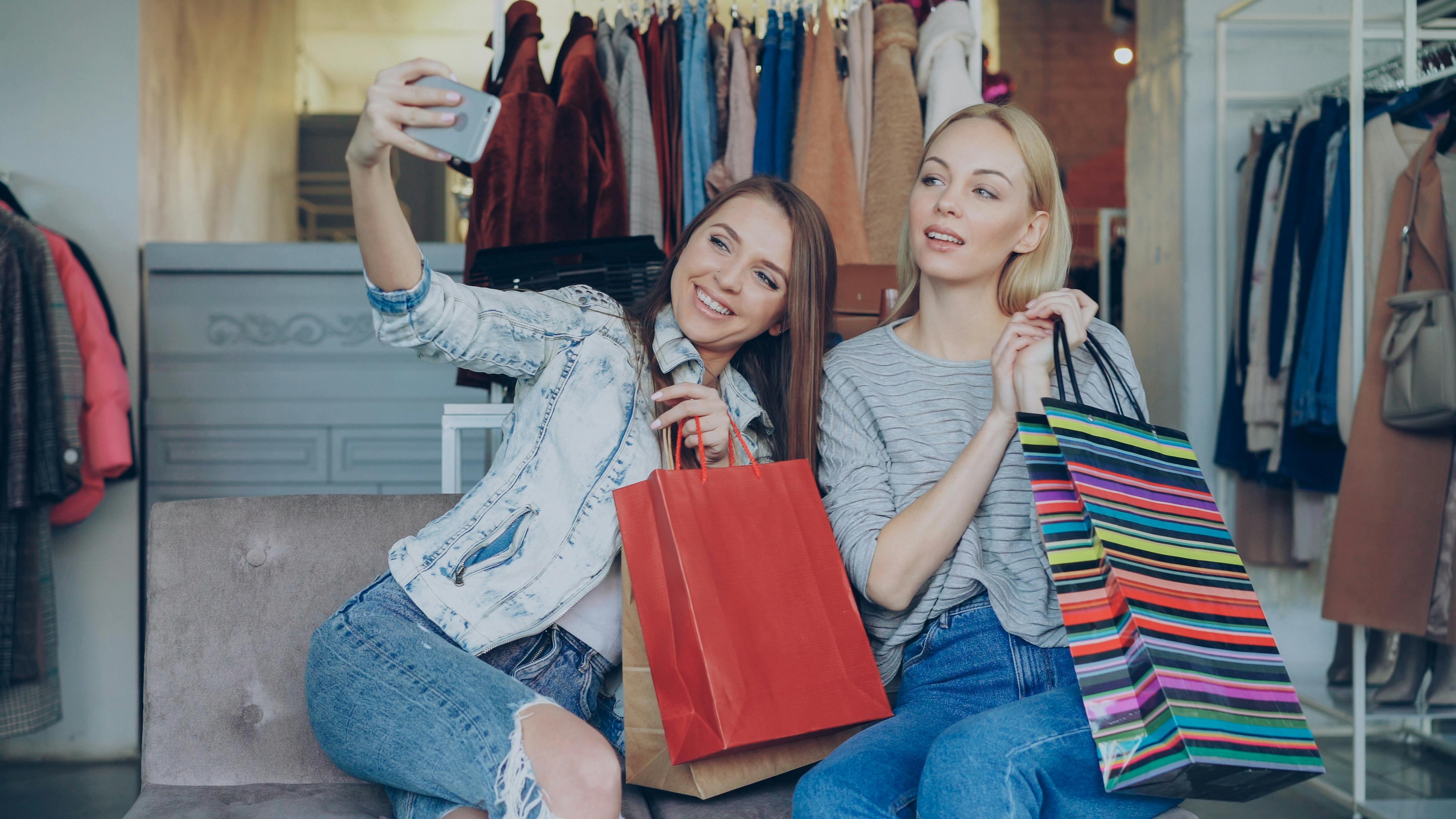 Two girls with shopping bags take a selfie