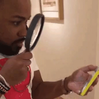 A guy reading a message in a mobile device through a magnifying glass